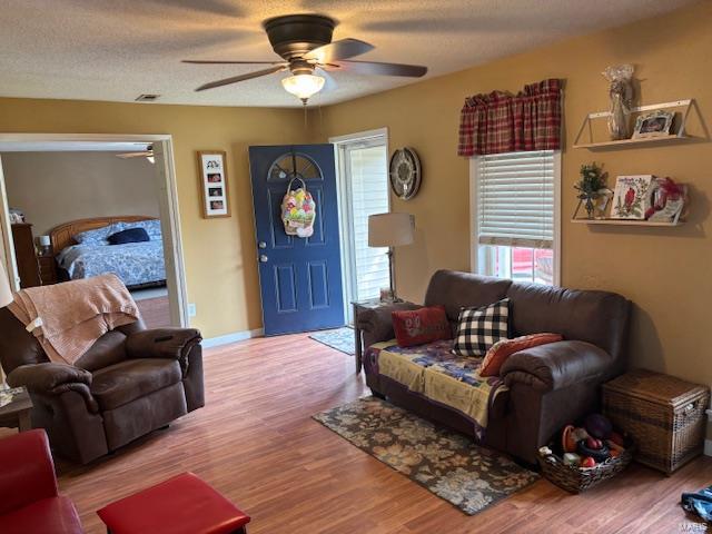 living room with a ceiling fan, wood finished floors, and baseboards