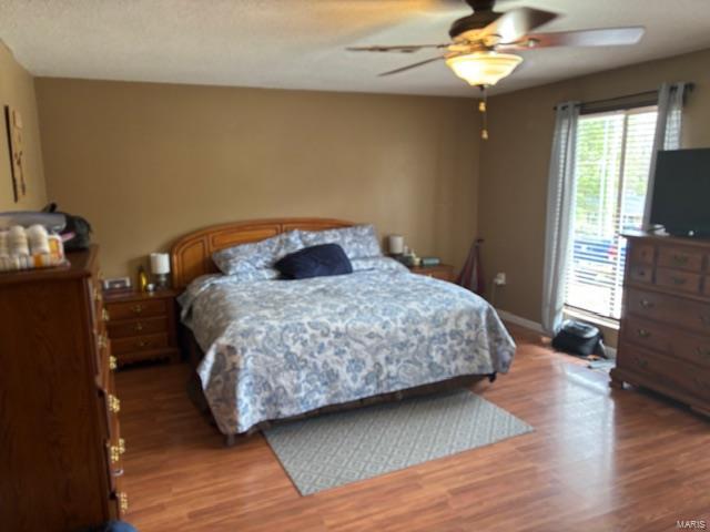 bedroom with light wood-type flooring, ceiling fan, and baseboards