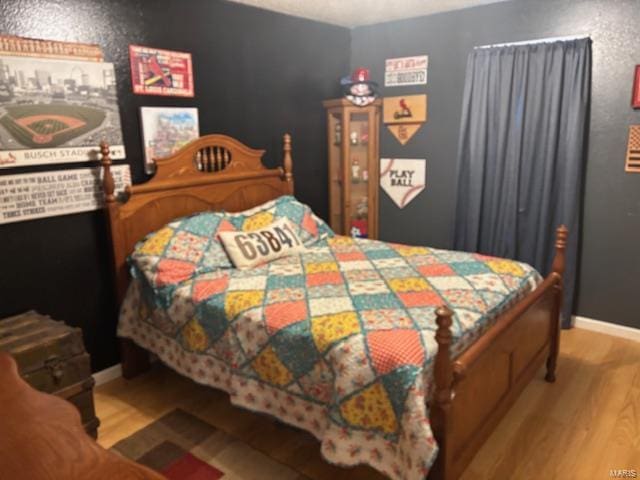bedroom featuring wood finished floors and baseboards