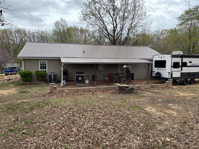 back of house with metal roof and central AC unit