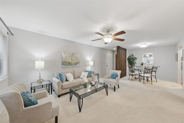 living area featuring a ceiling fan, light carpet, and baseboards