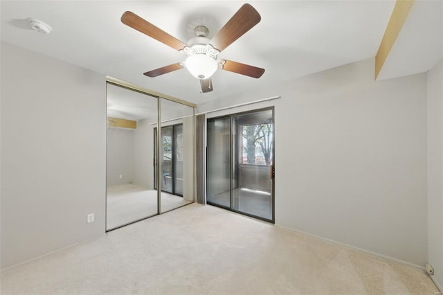 unfurnished bedroom with carpet flooring, access to exterior, a ceiling fan, and a closet