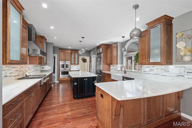 1416 Haarman Oak Dr, Wildwood, MO 63005 - kitchen with appliances with stainless steel finishes, wall chimney range hood, wood finished floors, backsplash, and recessed lighting