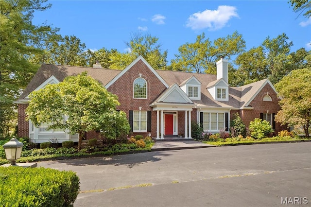 view of front of house featuring a chimney and brick siding