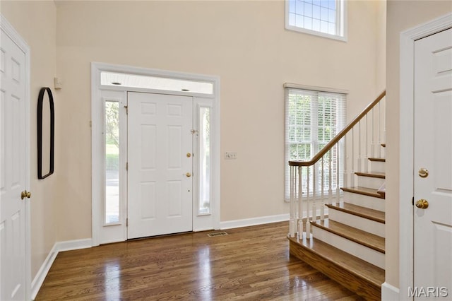 entryway featuring stairway, plenty of natural light, wood finished floors, and a high ceiling