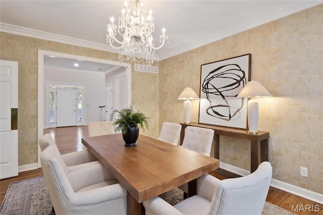 dining area featuring a chandelier, wood finished floors, baseboards, and ornamental molding