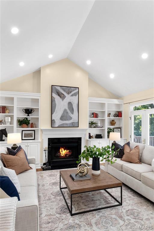 living area with lofted ceiling, a lit fireplace, recessed lighting, wood finished floors, and built in features