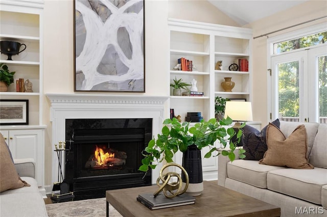 living room with a fireplace with flush hearth, vaulted ceiling, and built in shelves