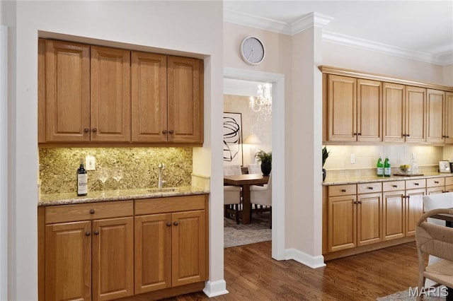 bar area featuring a sink, dark wood-style floors, backsplash, crown molding, and a chandelier