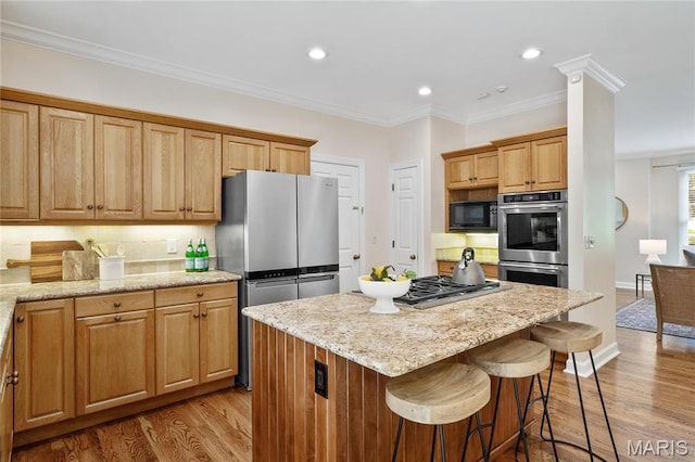 kitchen featuring appliances with stainless steel finishes, light wood-style floors, a center island, a kitchen bar, and recessed lighting