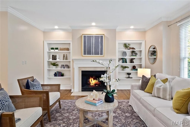 living area with healthy amount of natural light, built in shelves, a fireplace, crown molding, and recessed lighting