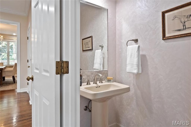 bathroom featuring crown molding, wood finished floors, and baseboards