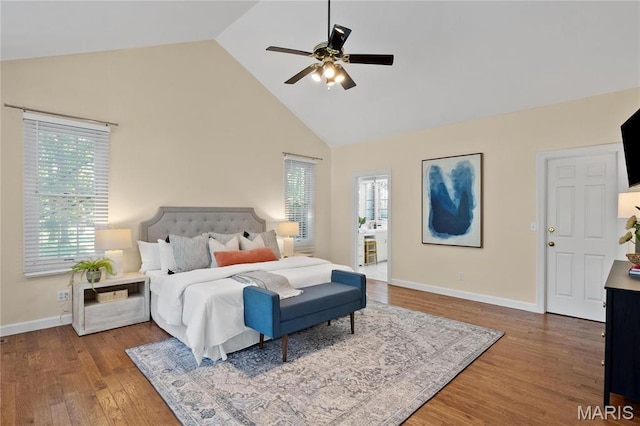bedroom featuring high vaulted ceiling, multiple windows, wood finished floors, baseboards, and a ceiling fan