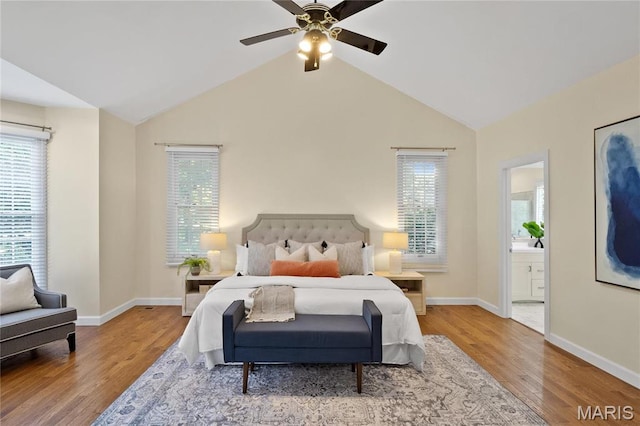 bedroom with multiple windows, wood finished floors, lofted ceiling, baseboards, and ensuite bath