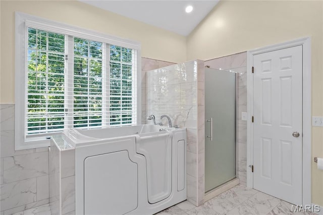 bathroom featuring marble look tiles, a stall shower, a bath, and tile walls