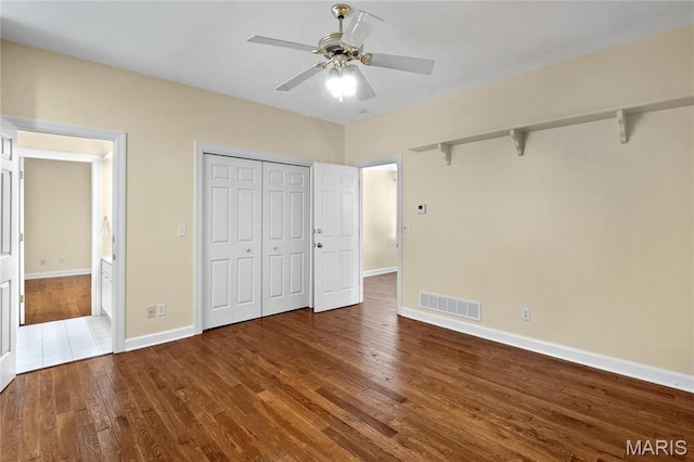 unfurnished bedroom with wood finished floors, baseboards, ceiling fan, and a closet