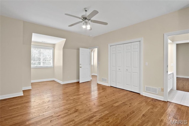 unfurnished bedroom featuring wood finished floors, a closet, baseboards, and a ceiling fan