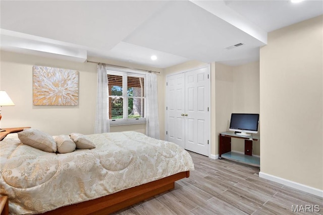 bedroom with recessed lighting, light wood-style floors, baseboards, and a closet