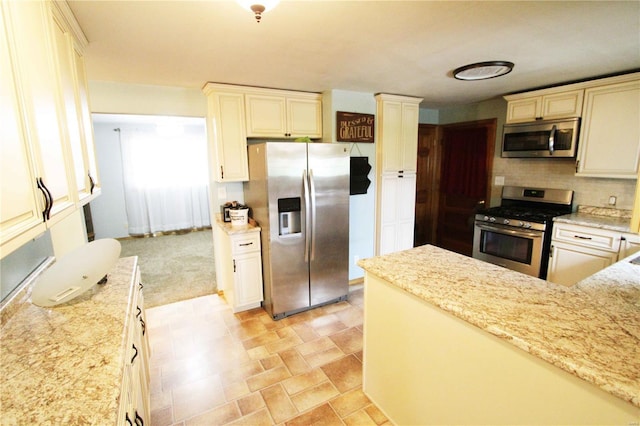 634 Ccam Rose Ln, Perryville, MO 63775 - kitchen featuring appliances with stainless steel finishes, tasteful backsplash, light stone countertops, and cream cabinetry