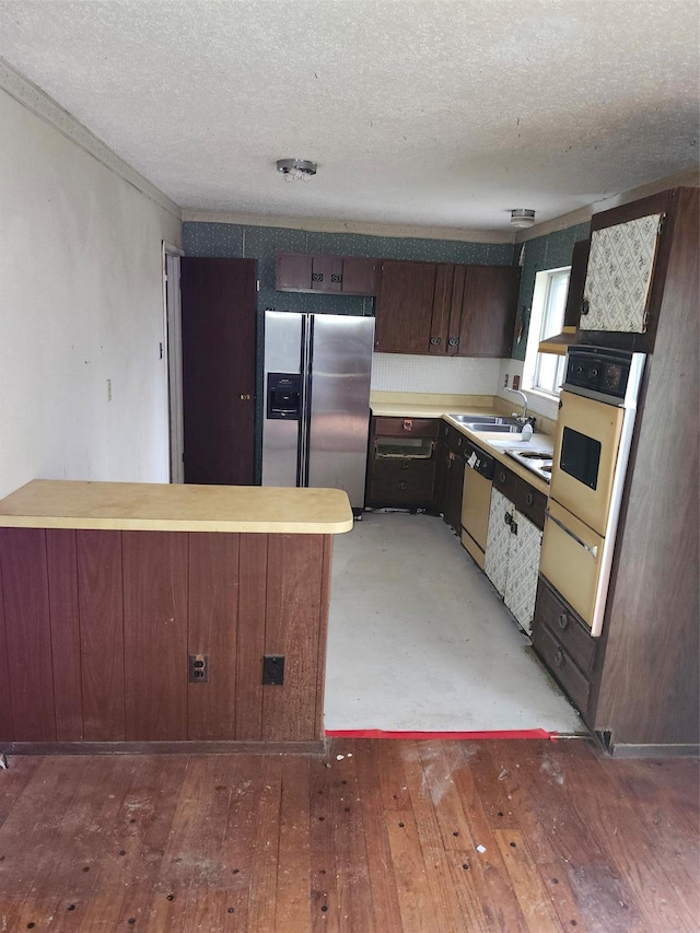 6081 Silver Fox Dr, Florissant, MO 63034 - kitchen with stainless steel appliances, a peninsula, a textured ceiling, light wood-style floors, and light countertops