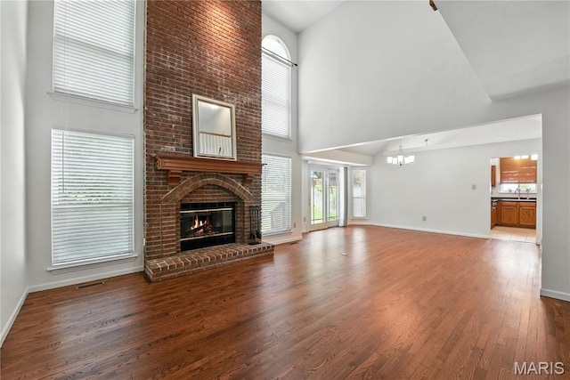 1827 Pheasant Run Dr, Maryland Heights, MO 63043 - unfurnished living room featuring high vaulted ceiling, a fireplace, a chandelier, and wood finished floors
