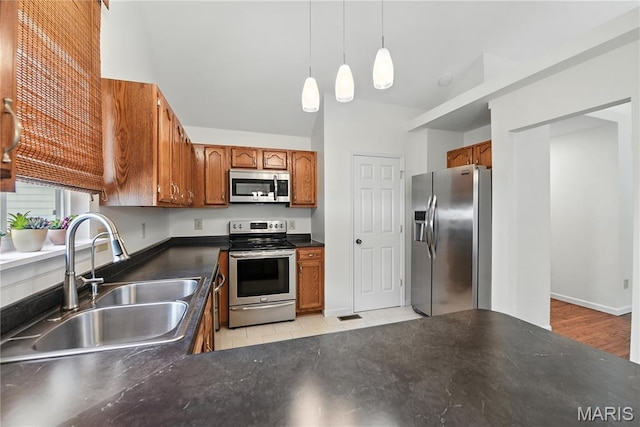1827 Pheasant Run Dr, Maryland Heights, MO 63043 - kitchen featuring stainless steel appliances, dark countertops, brown cabinetry, and hanging light fixtures