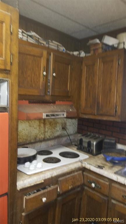 206 N 11th St, Coulterville, IL 62237 - kitchen with white electric cooktop, light countertops, brown cabinetry, and extractor fan