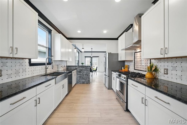 713 Alban Aly, Ofallon, MO 63368 - kitchen featuring stainless steel appliances, wall chimney exhaust hood, a sink, light wood-style flooring, and healthy amount of natural light