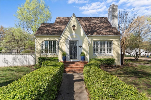 669 Park Ave, Sikeston, MO 63801 - tudor house featuring a chimney, fence, a shingled roof, and stucco siding