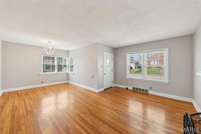 8724 Magdalen Ave, Saint Louis, MO 63144 - unfurnished living room featuring light wood finished floors, baseboards, and a chandelier