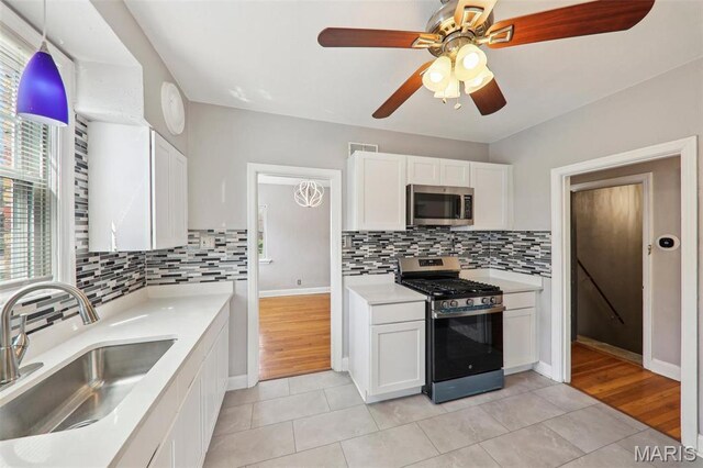 8724 Magdalen Ave, Saint Louis, MO 63144 - kitchen featuring stainless steel appliances, a sink, light tile patterned floors, and white cabinetry