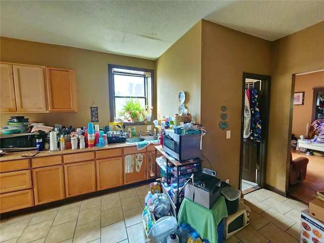 4052 Detonty St, Saint Louis, MO 63110 - kitchen with stainless steel microwave, light tile patterned floors, a textured ceiling, light countertops, and a sink