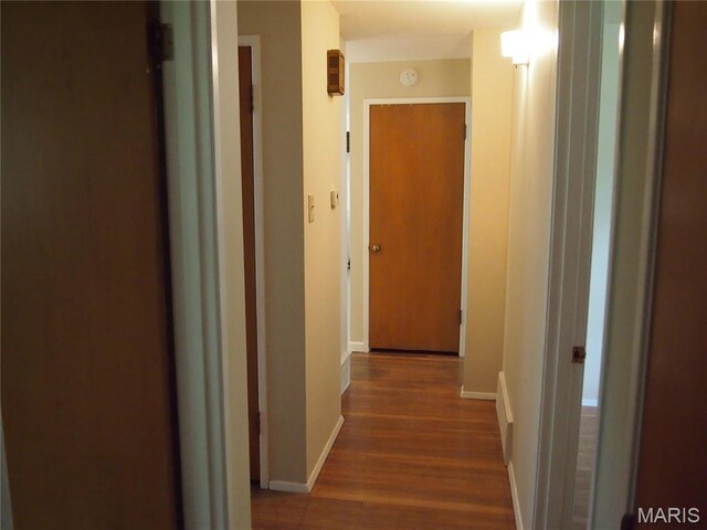 corridor with wood finished floors and baseboards