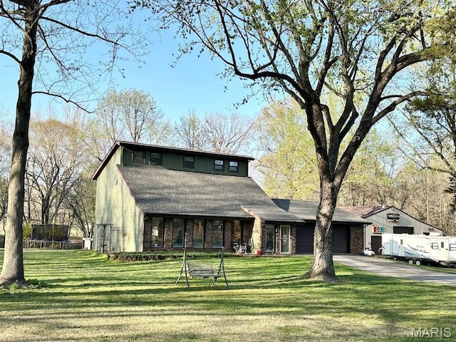 view of front of property featuring a trampoline, a garage, driveway, and a front yard