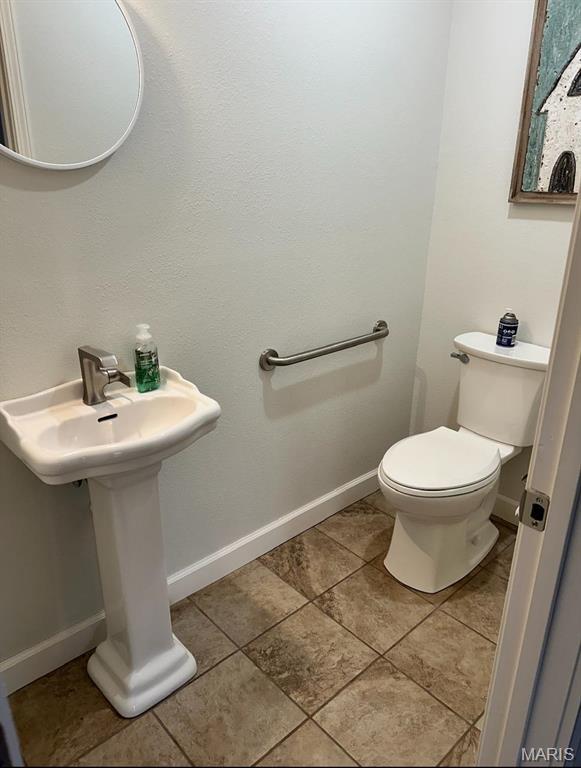 half bathroom featuring toilet, baseboards, and tile patterned flooring