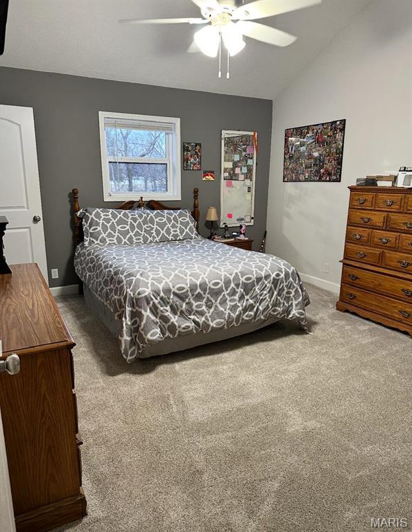 carpeted bedroom featuring baseboards, lofted ceiling, and a ceiling fan
