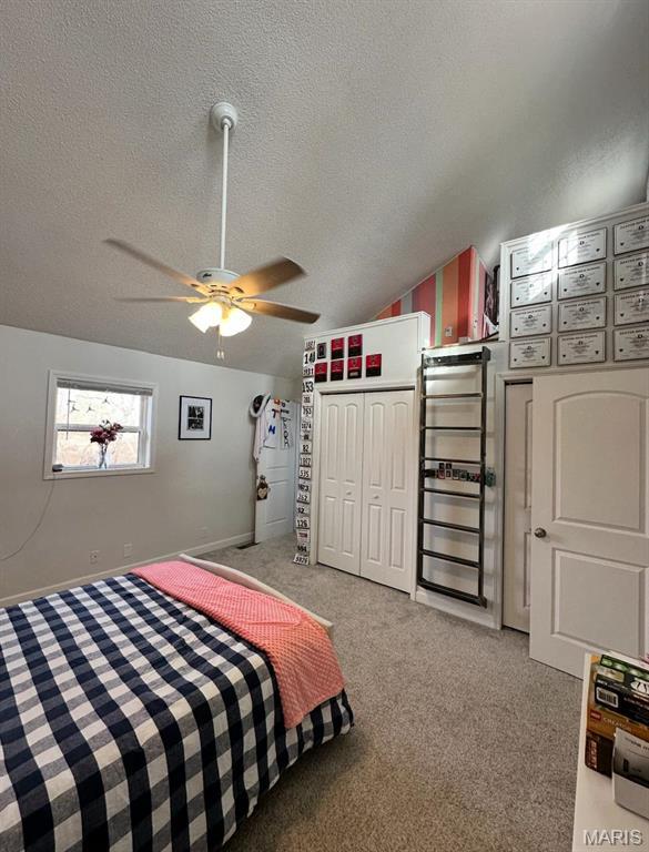 bedroom with light carpet, a textured ceiling, vaulted ceiling, a ceiling fan, and baseboards