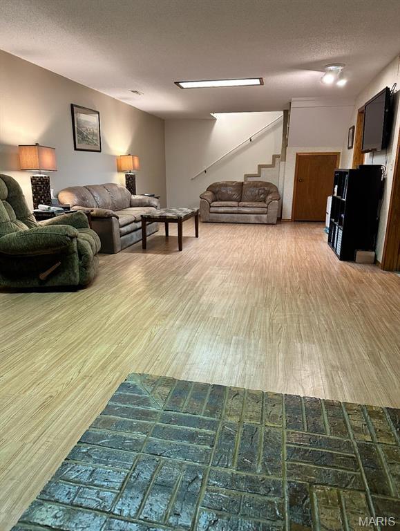 living room featuring wood finished floors, stairway, and a textured ceiling