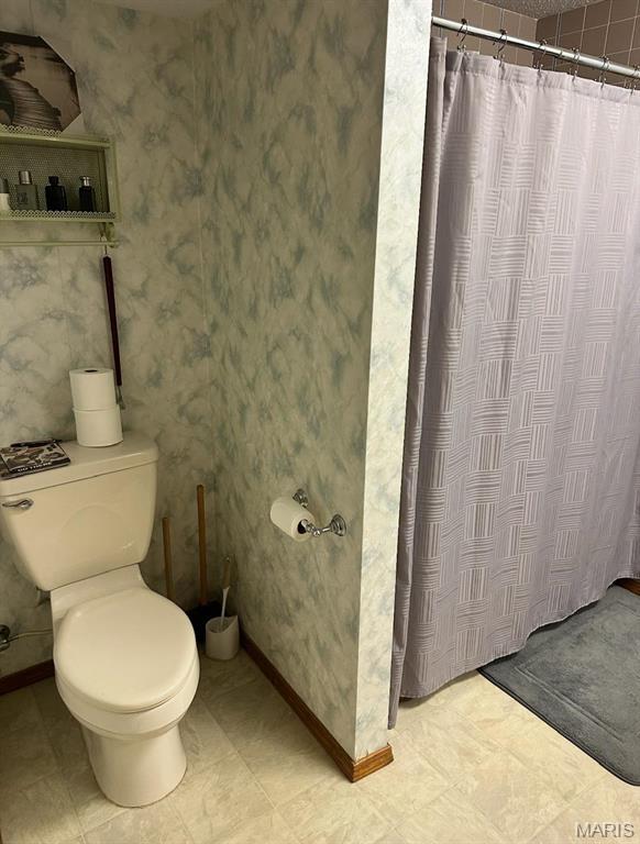 full bath with toilet, a shower with shower curtain, baseboards, and wallpapered walls