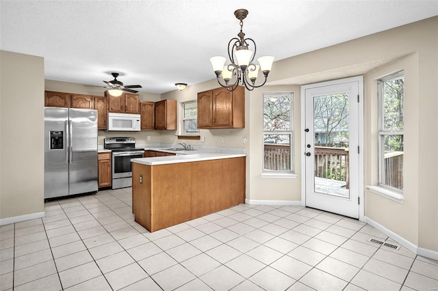 413 Oak Pl, Lake St Louis, MO 63367 - kitchen with stainless steel appliances, a peninsula, a sink, light countertops, and brown cabinetry