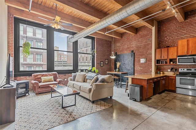living area featuring brick wall, wooden ceiling, finished concrete floors, a wood stove, and beam ceiling