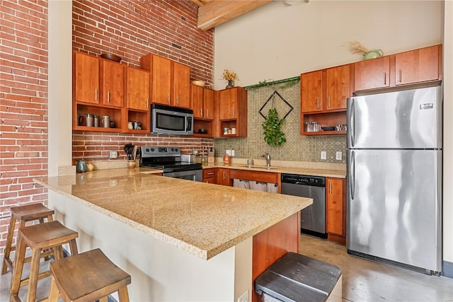 kitchen featuring appliances with stainless steel finishes, open shelves, a peninsula, brown cabinets, and a high ceiling