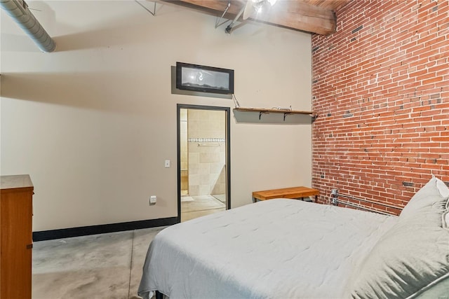 bedroom with brick wall, baseboards, concrete floors, beamed ceiling, and connected bathroom