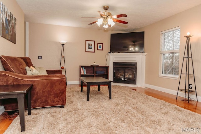 17145 Lensman Rd, Saint Robert, MO 65584 - living area with a glass covered fireplace, wood finished floors, ceiling fan, and baseboards