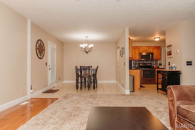 17145 Lensman Rd, Saint Robert, MO 65584 - living area featuring a chandelier, a textured ceiling, light tile patterned floors, and baseboards
