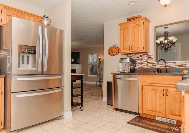 17145 Lensman Rd, Saint Robert, MO 65584 - kitchen with appliances with stainless steel finishes, a textured ceiling, light brown cabinets, a sink, and decorative backsplash