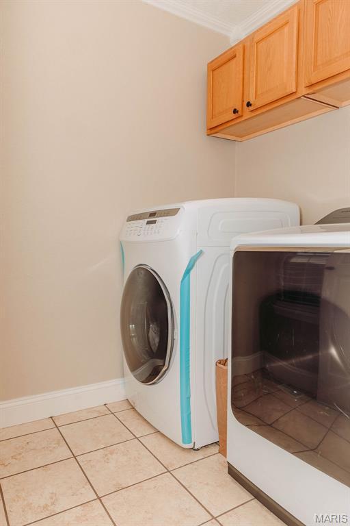 17145 Lensman Rd, Saint Robert, MO 65584 - laundry area with washer and clothes dryer, cabinet space, light tile patterned flooring, and baseboards