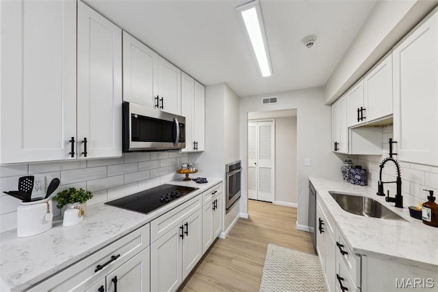 539 Coeur De Royale Dr Unit 201, Saint Louis, MO 63141 - kitchen featuring stainless steel appliances, a sink, decorative backsplash, baseboards, and white cabinets