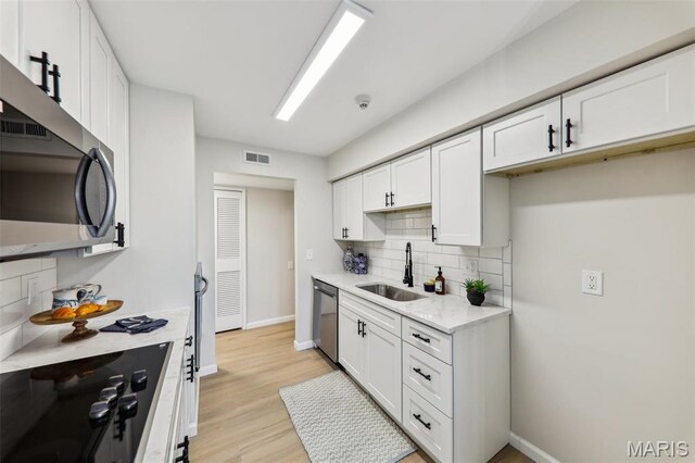 539 Coeur De Royale Dr Unit 201, Saint Louis, MO 63141 - kitchen with a sink, stainless steel appliances, backsplash, white cabinets, and baseboards