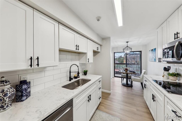 539 Coeur De Royale Dr Unit 201, Saint Louis, MO 63141 - kitchen with stainless steel microwave, black electric cooktop, a sink, white cabinetry, and decorative backsplash